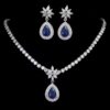 Elegant sapphire and crystal teardrop necklace and earring set with floral accents on black background