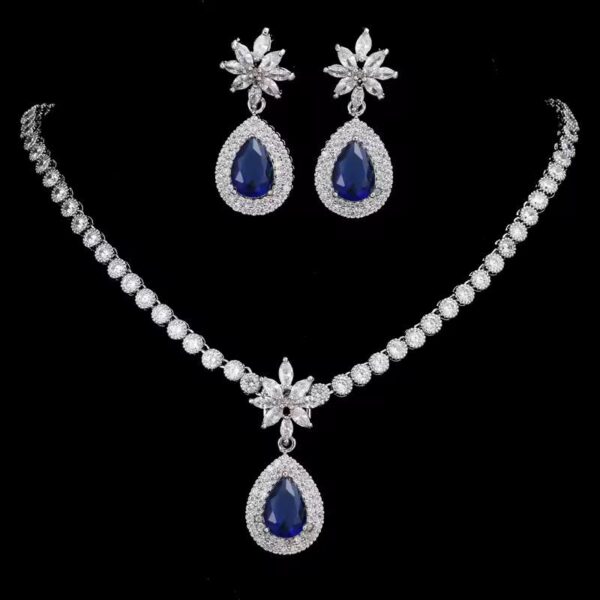 Elegant sapphire and crystal teardrop necklace and earring set with floral accents on black background