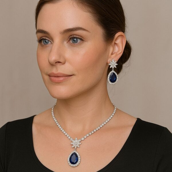 Elegant sapphire and crystal teardrop necklace and earring set with floral accents on black background model