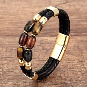 Braided black leather bracelet with multicolor tiger eye beads and gold magnetic clasp on wood surface